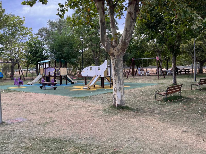 Parque infantil de Santa Eulalia de Tábara, con juegos, columpios y bancos bajo los árboles.