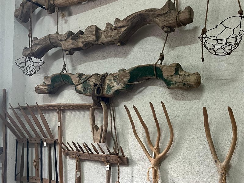 Yugos de madera, horcas y bieldos colgados en una pared del museo