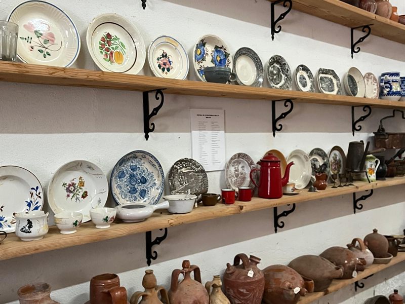 Estantes con platos decorados, cántaros de barro y cacharros de cocina del museo